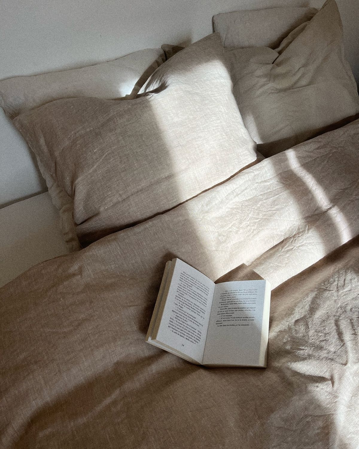 taie d'oreiller en lin beige avec un livre posé sur le lit 