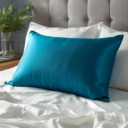 une taie d'oreiller en soie bleu paon sur lit blanc 